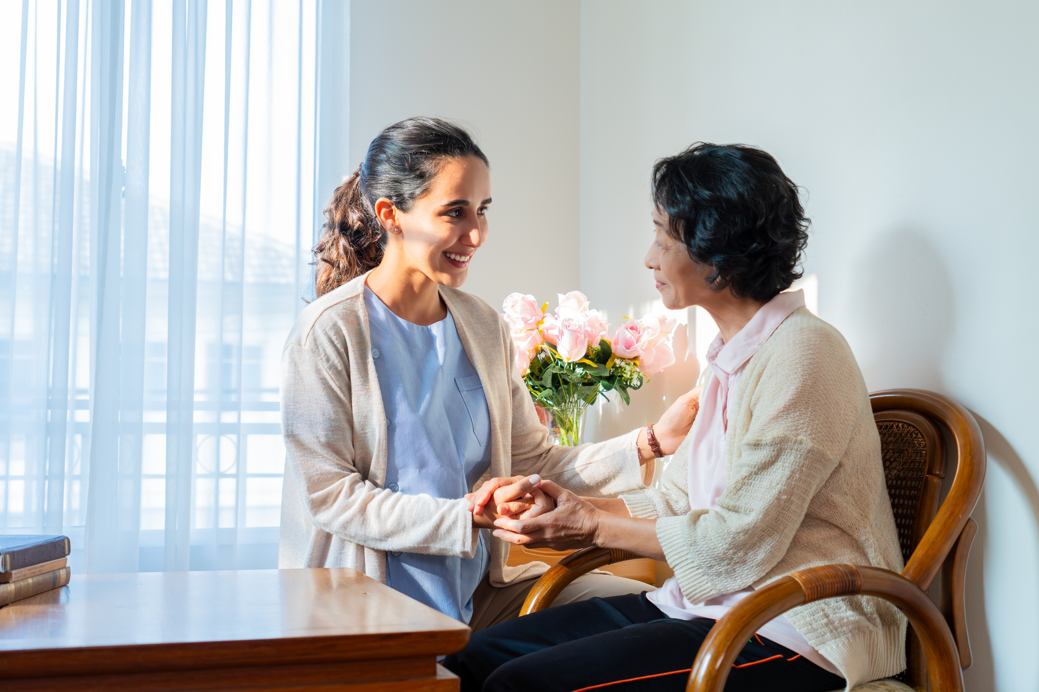 Caregiver holds hands with an older woman during an in-home respite care visit.